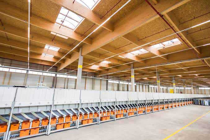 Large logistics warehouse interior with racking, picking aisles and high clear height.